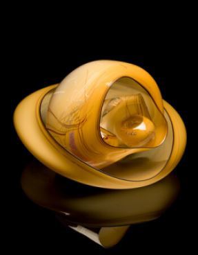A smooth, yellow-brown glass vessel with a wide oval containing a basket-shaped form and several smaller glass forms.