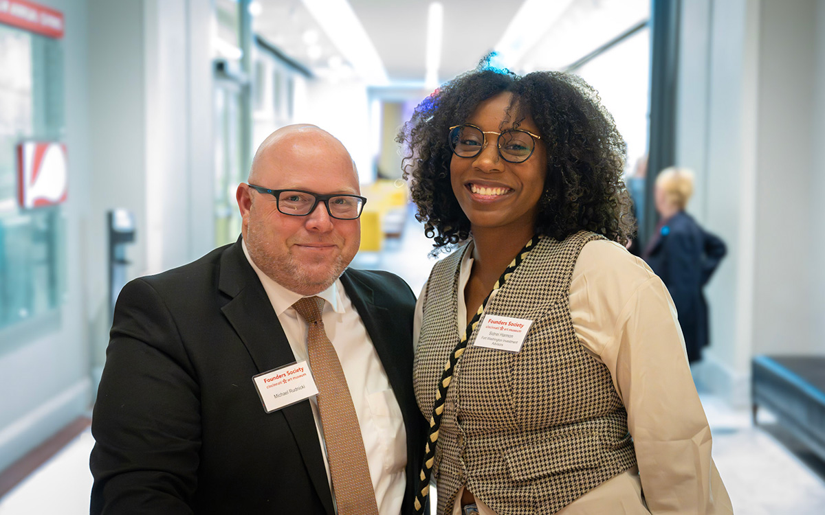 A nicely-dressed white man and Black woman smile for the camera