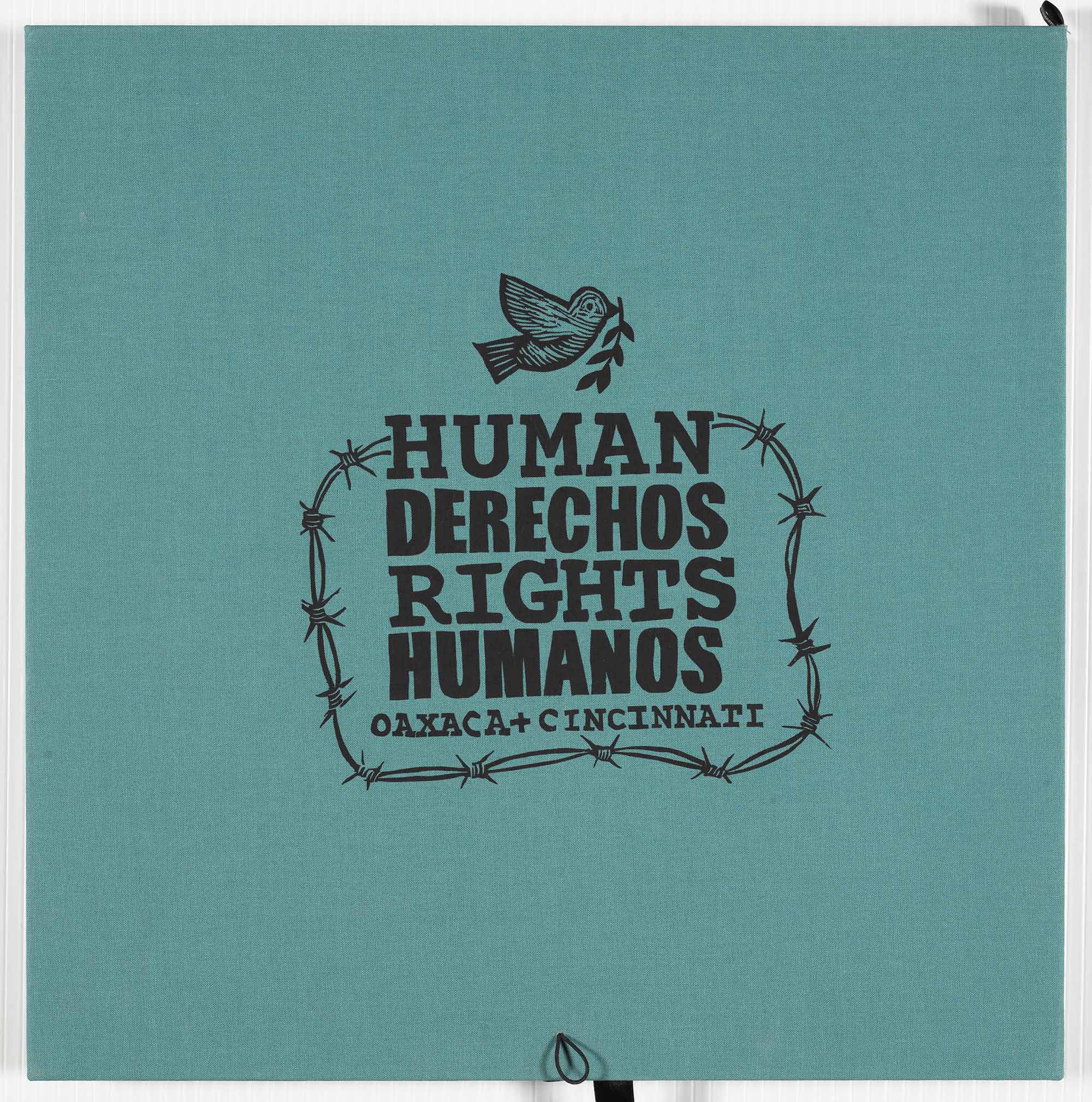 A print that reads "Human Rights / Derechos Humanos, Oaxaca + Cincinnati" in barbed wire, with a dove holding an olive branch flying above