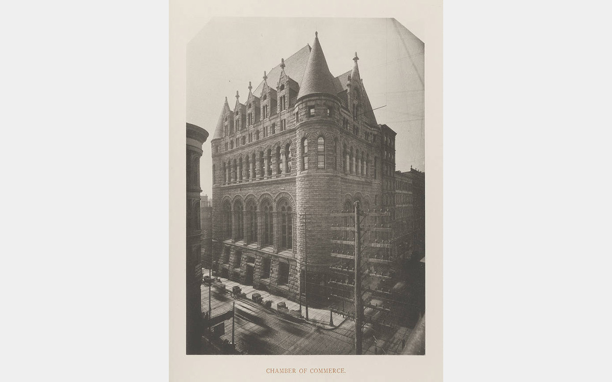 Black and white photo of castle-like stone building in an urban setting