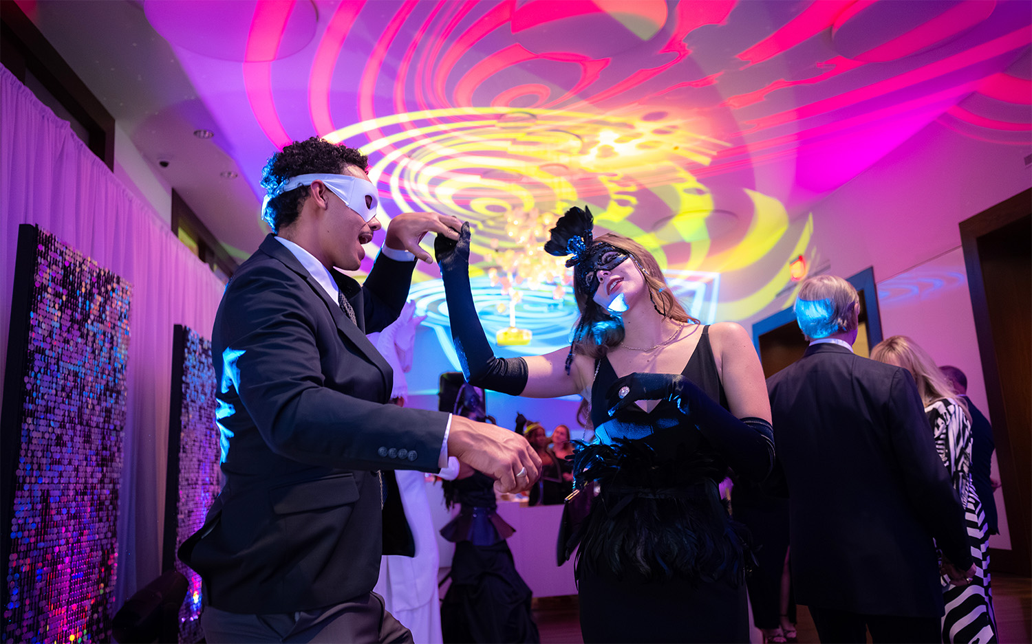 A couple dances in a colorfully lit room