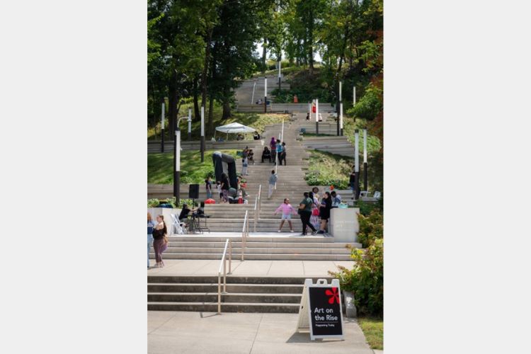 Stone staircase winding up a wooded hillside with people on it.