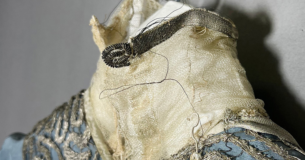 Detail of the neck of a dress. It is discolored, with loose threads.