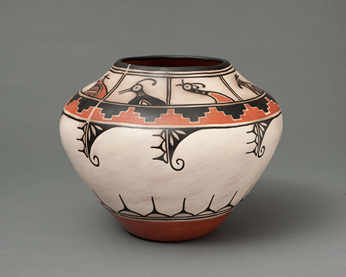 A ceramic vessel with a wide white band around the middle, with a band featuring stylized bird figures above