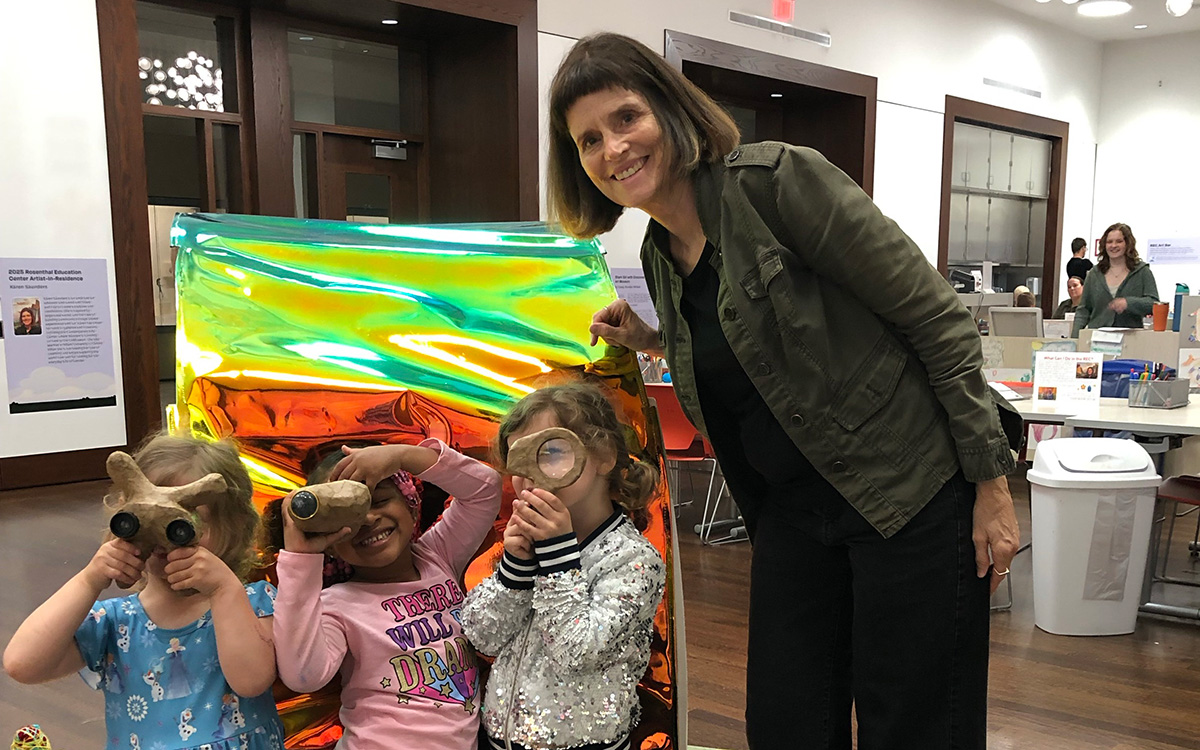 A woman poses with three young kids holding up wooden viewfinders
