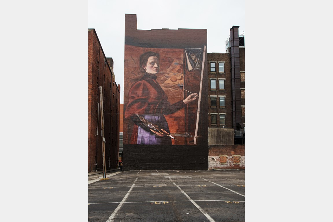 Outdoor mural depicting a woman painting with palette and canvass.