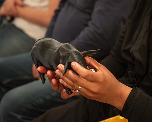 Participants hold handmade masks up to their faces for a photo