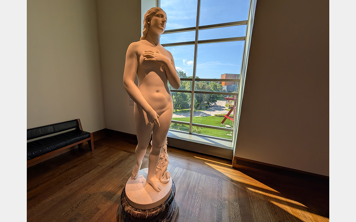 White marble sculpture of a woman in front of a window