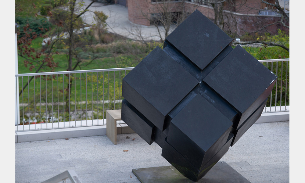 A black cube made up of smaller cubes standing on one of its corners