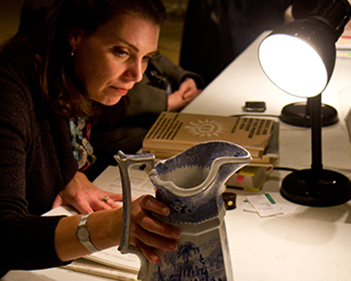 a curator inspecting a pitcher