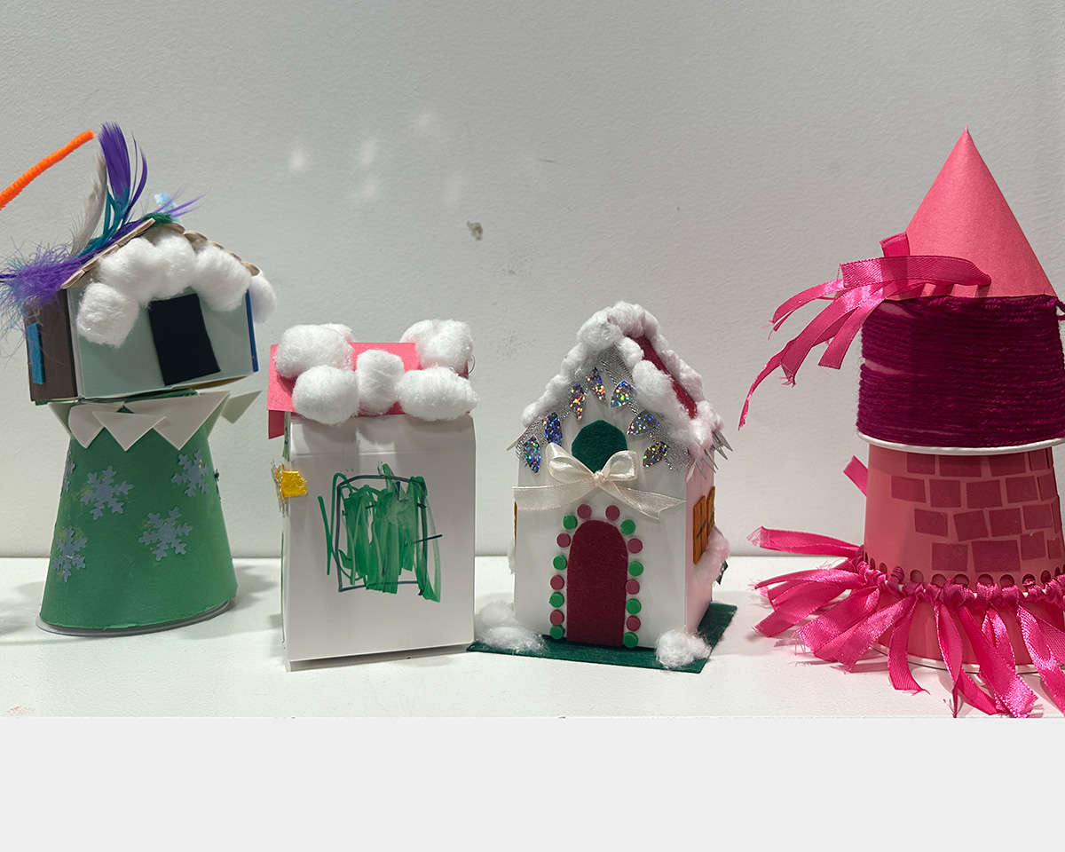 Four toy houses made of paper and assorted colorful materials.