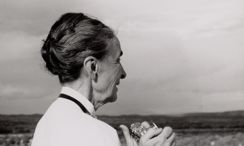A black and white photo of Georgia O'Keeffe holding a camera