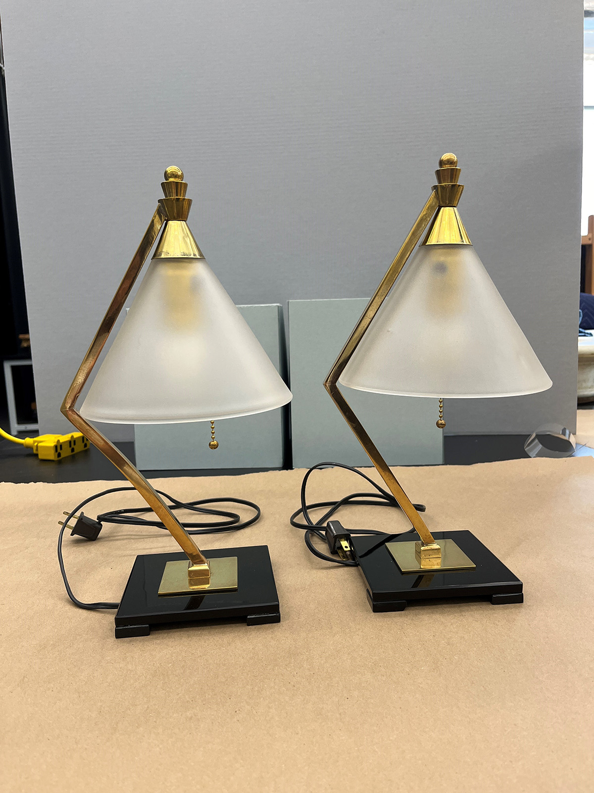 Two angular lamps with gold fixtures, opaque glass shades, and shiny black bases