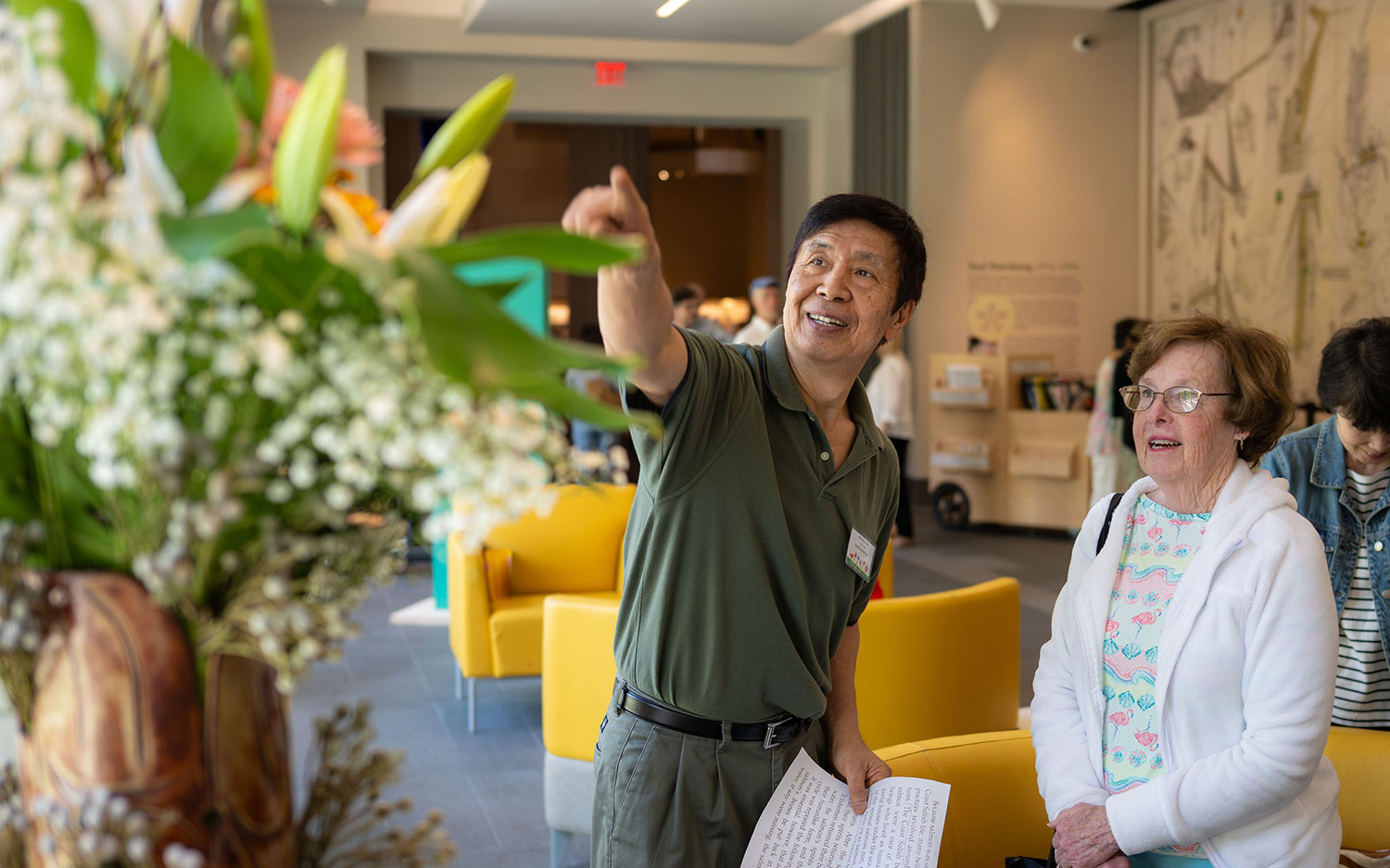 An Asian man points to a floral arrangement