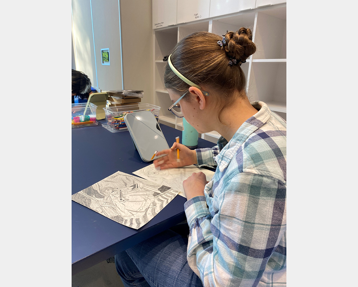 Girl sits at a table and makes sketches.