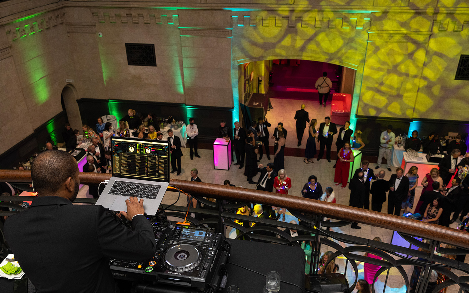 A Black DJ overlooks partygoers in the Great Hall