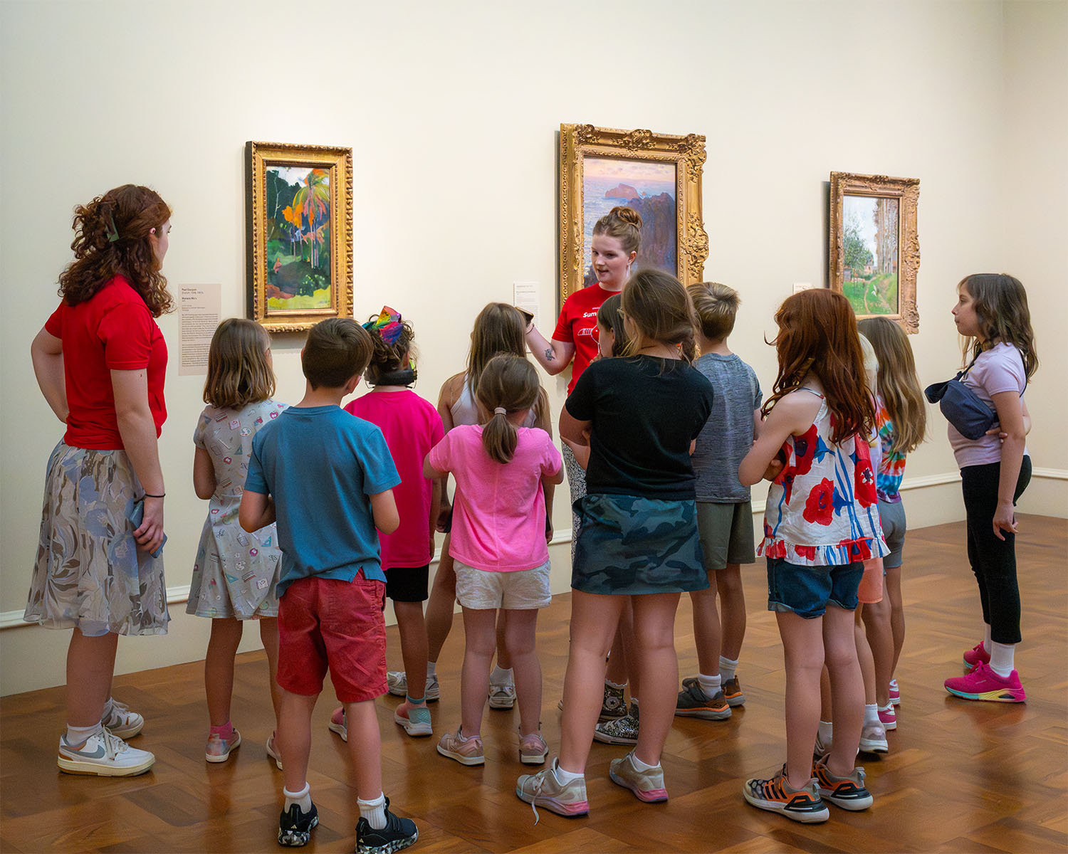 Chaperones guide a large group of young students through a gallery