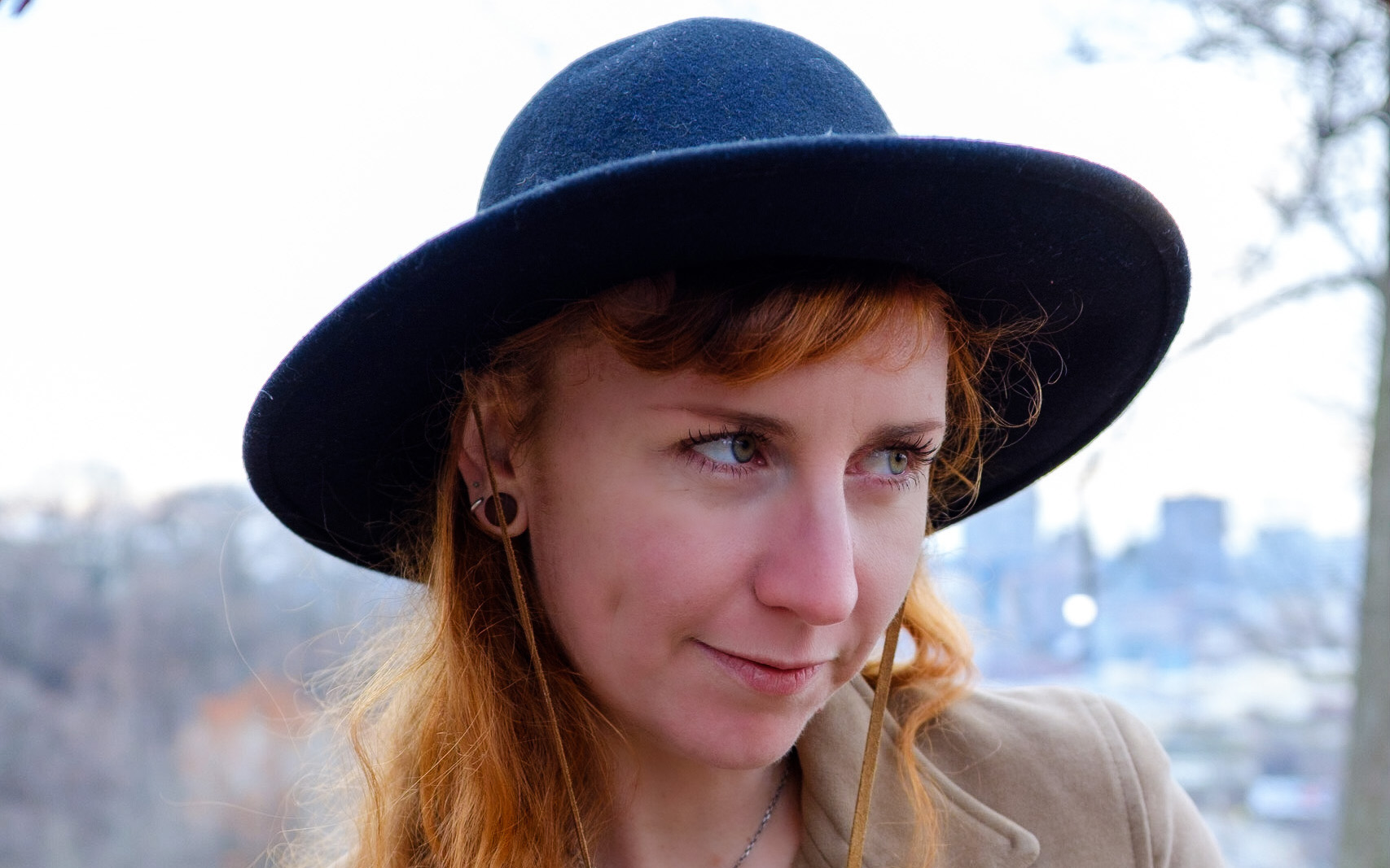 A white woman with red hair and a big, dark hat