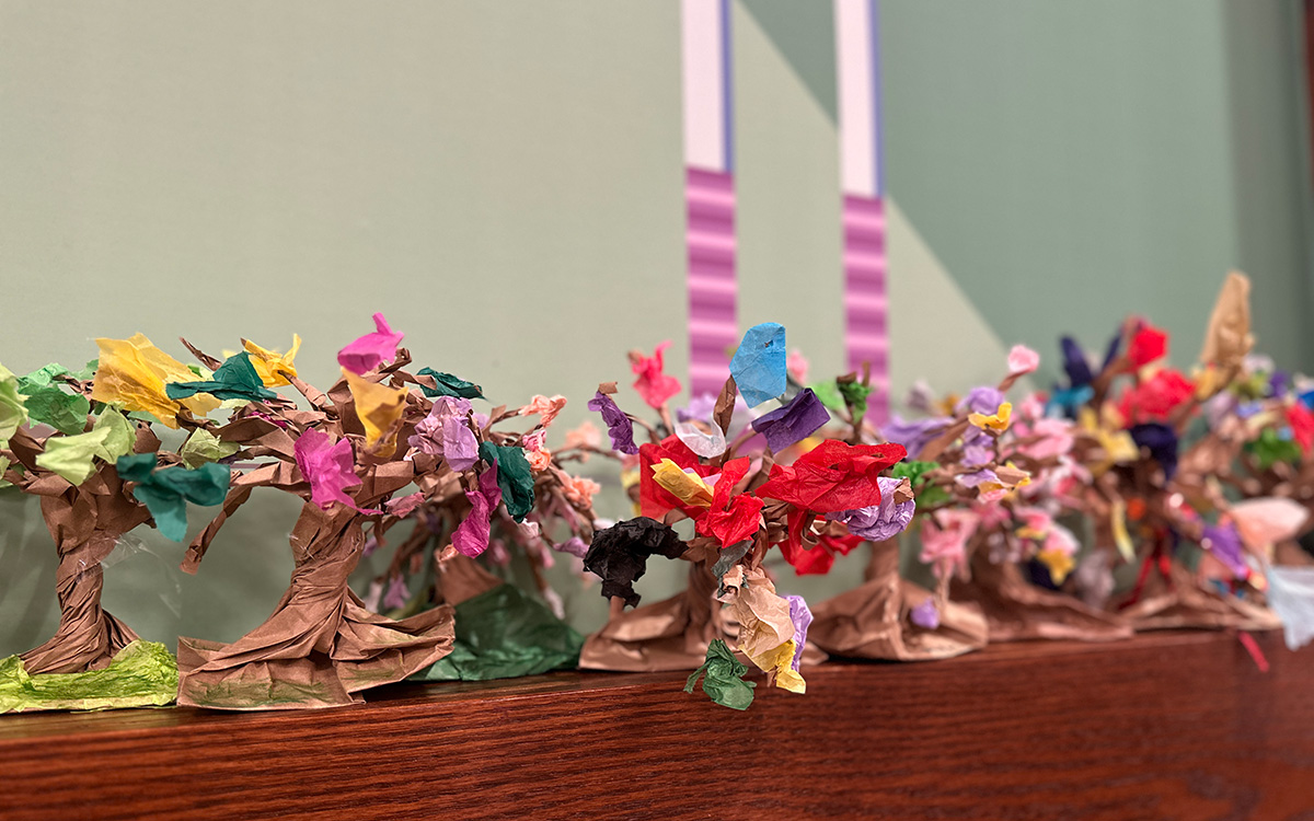 Sculptures -- made of colorful paper and representing tree-like forms -- sit on a wood shelf.