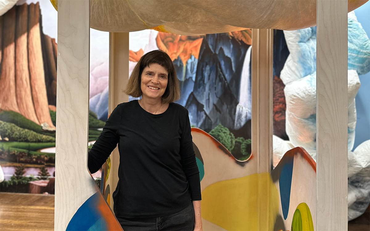 A white woman smiles and poses with the installation