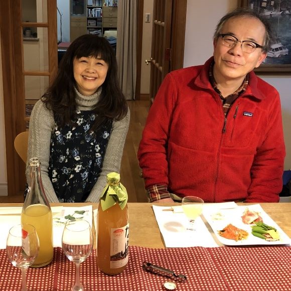 A woman (left) and a man (right) sit at a dining table with dinner plates and beverage bottles.