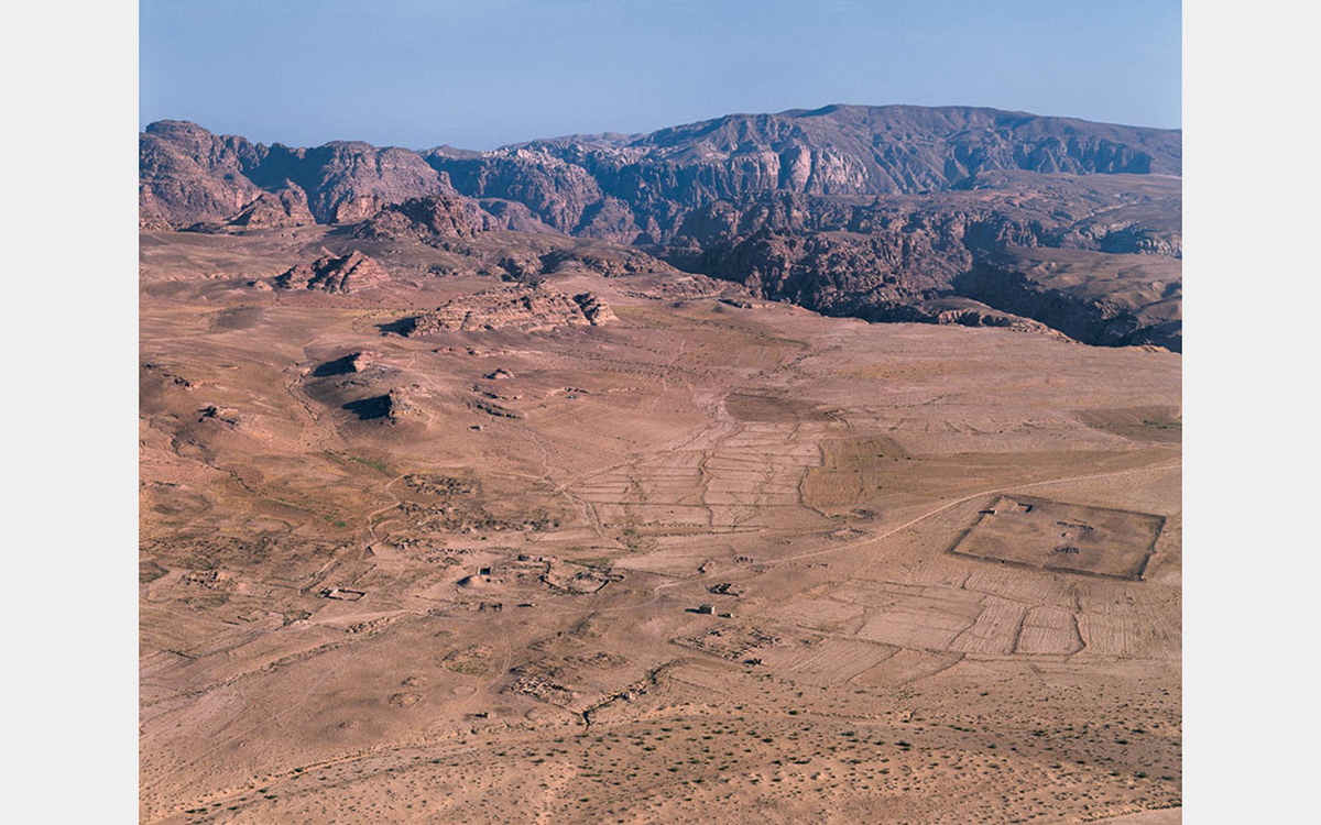 Brown arid landscape with mountains in background and a cloudless sky.