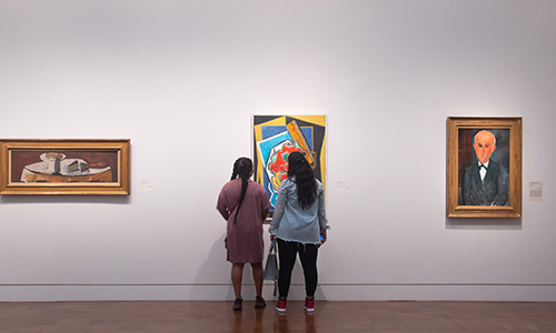 Two Black women look at a painting in gallery