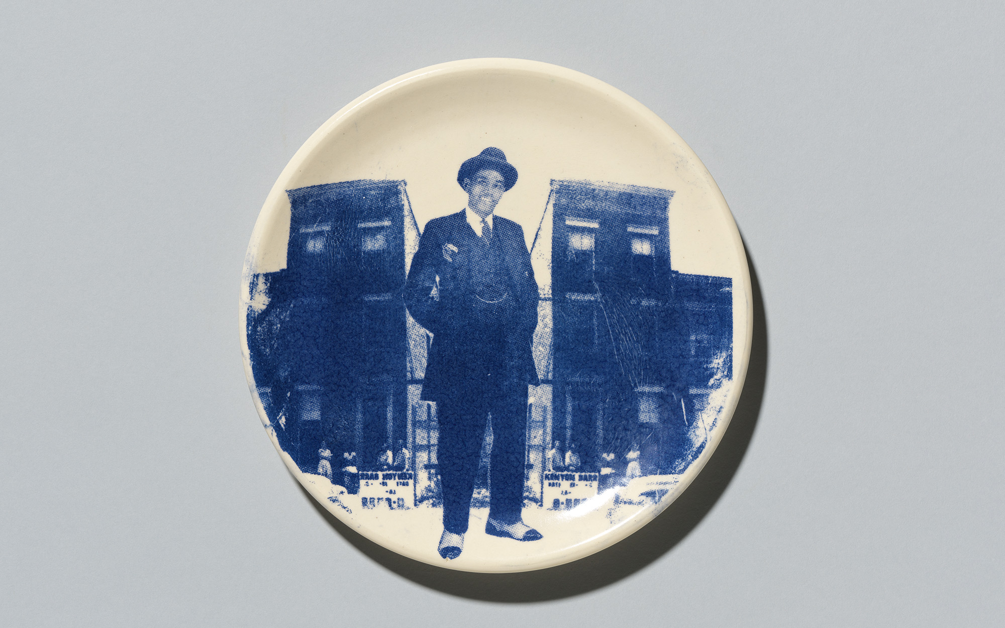 A plate with a blue print of a Black man standing in front of two buildings