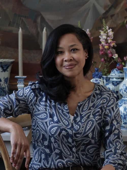 Natasja Sadi smiles at the camera in front of a table with candles and floral arrangement