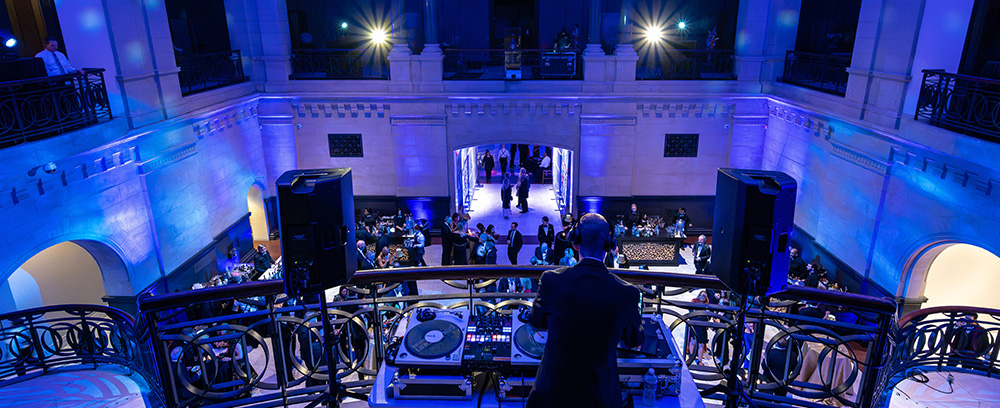 A DJ set up on a balcony overlooking the Great Hall