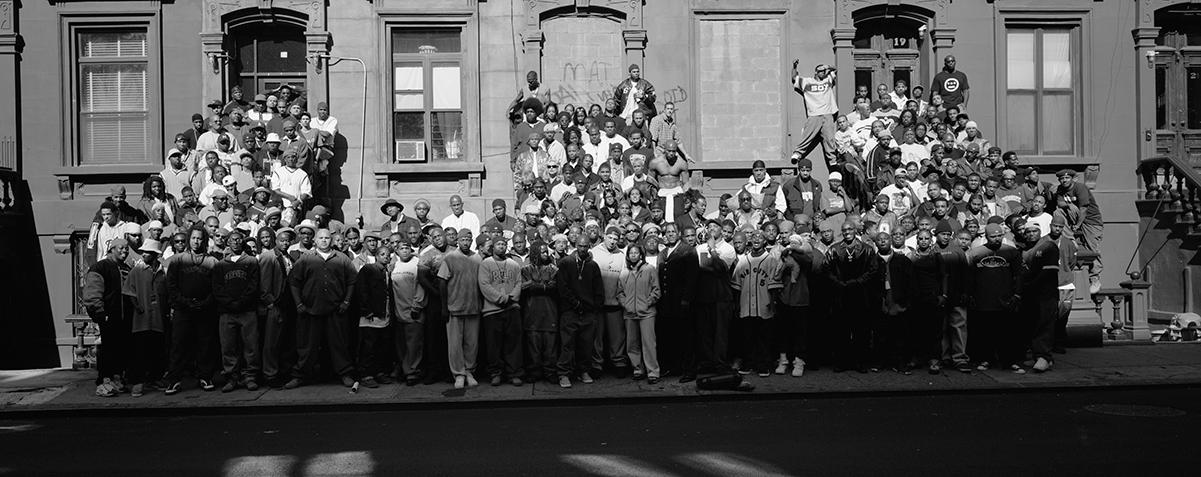 A black and white photo of dozens of Black people standing on three staircases