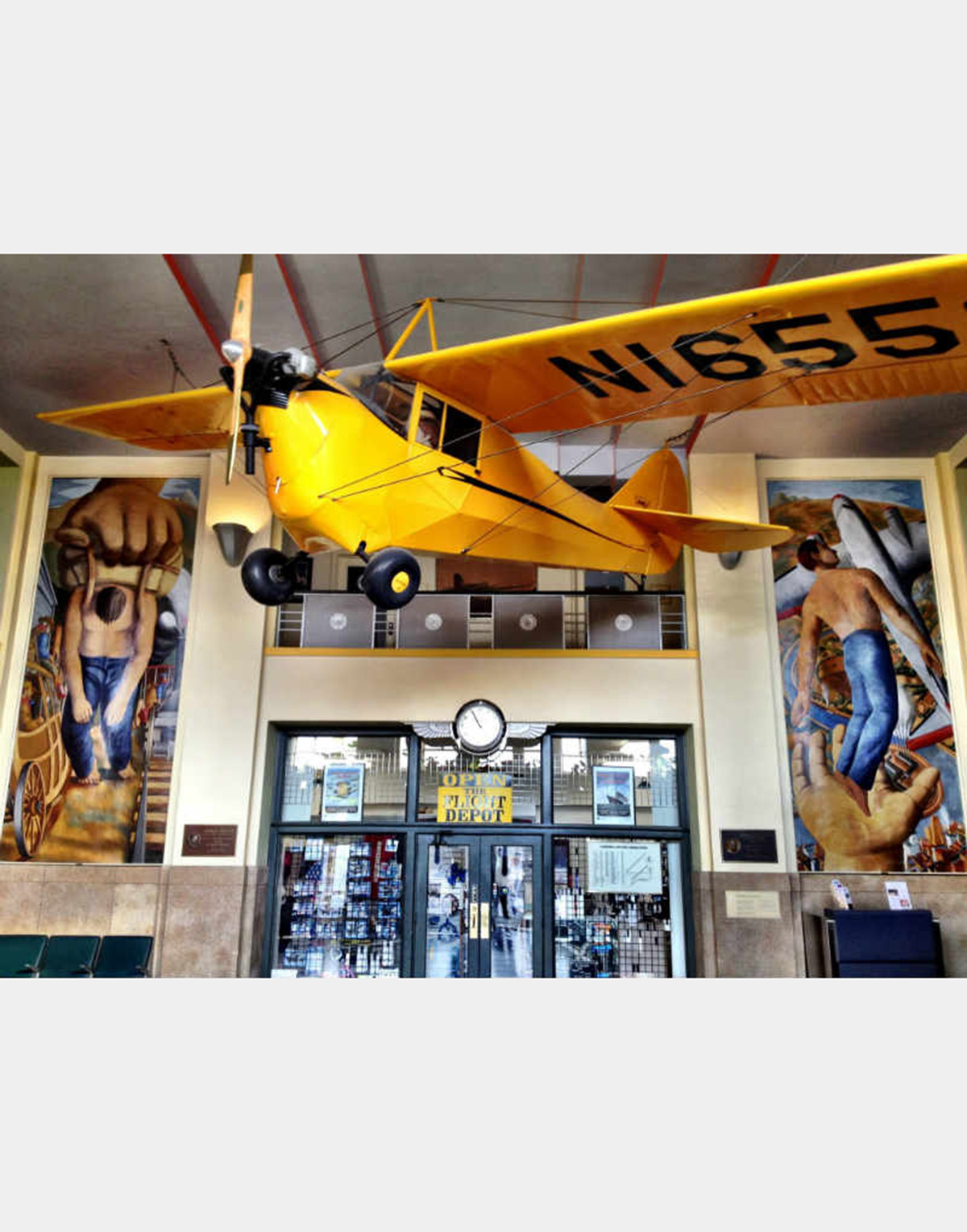 A yellow airplane hangs inside a large building