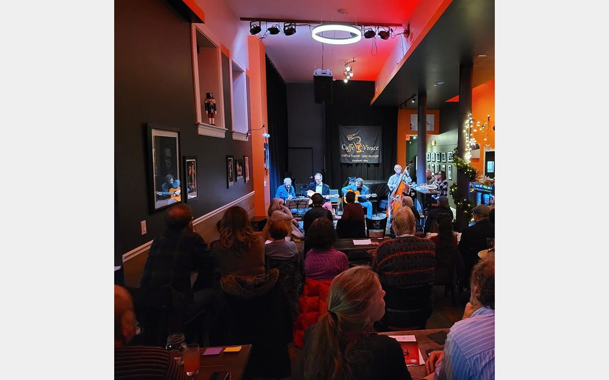 People sitting with back towards camera watching musicians highlighted in background