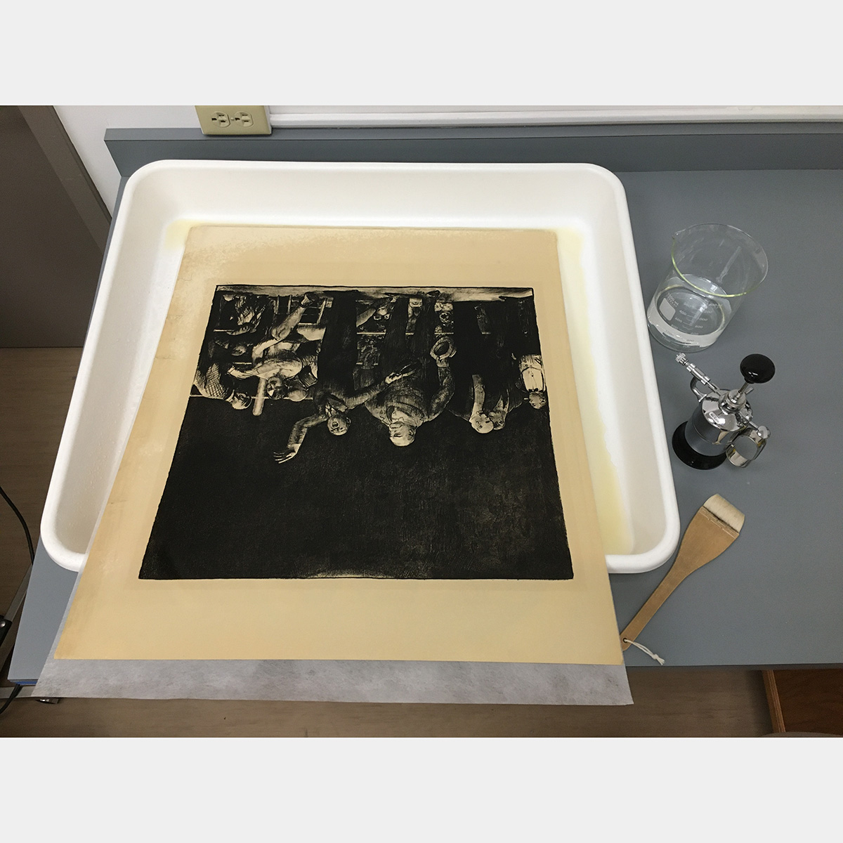 A yellowed print sits in a large white plastic tub