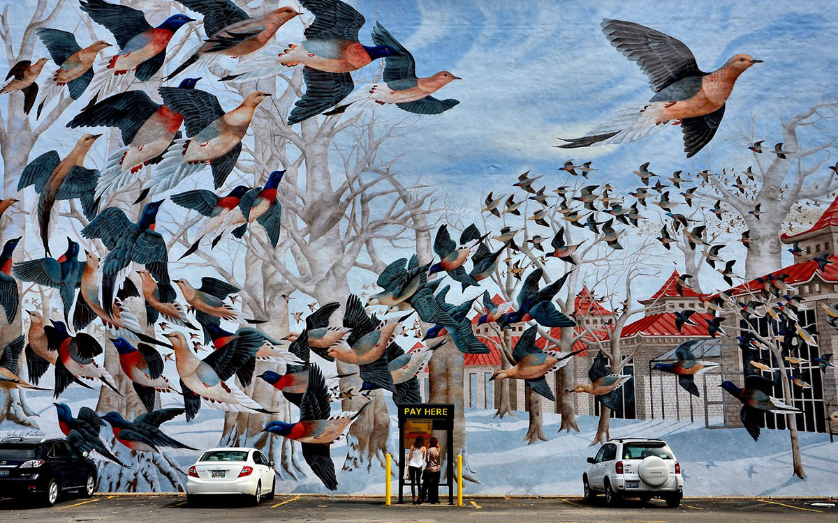 Large outdoor mural on the side of building facing a parking lot; mural depicts a flock of birds and a line of Chinese-style pavilions.