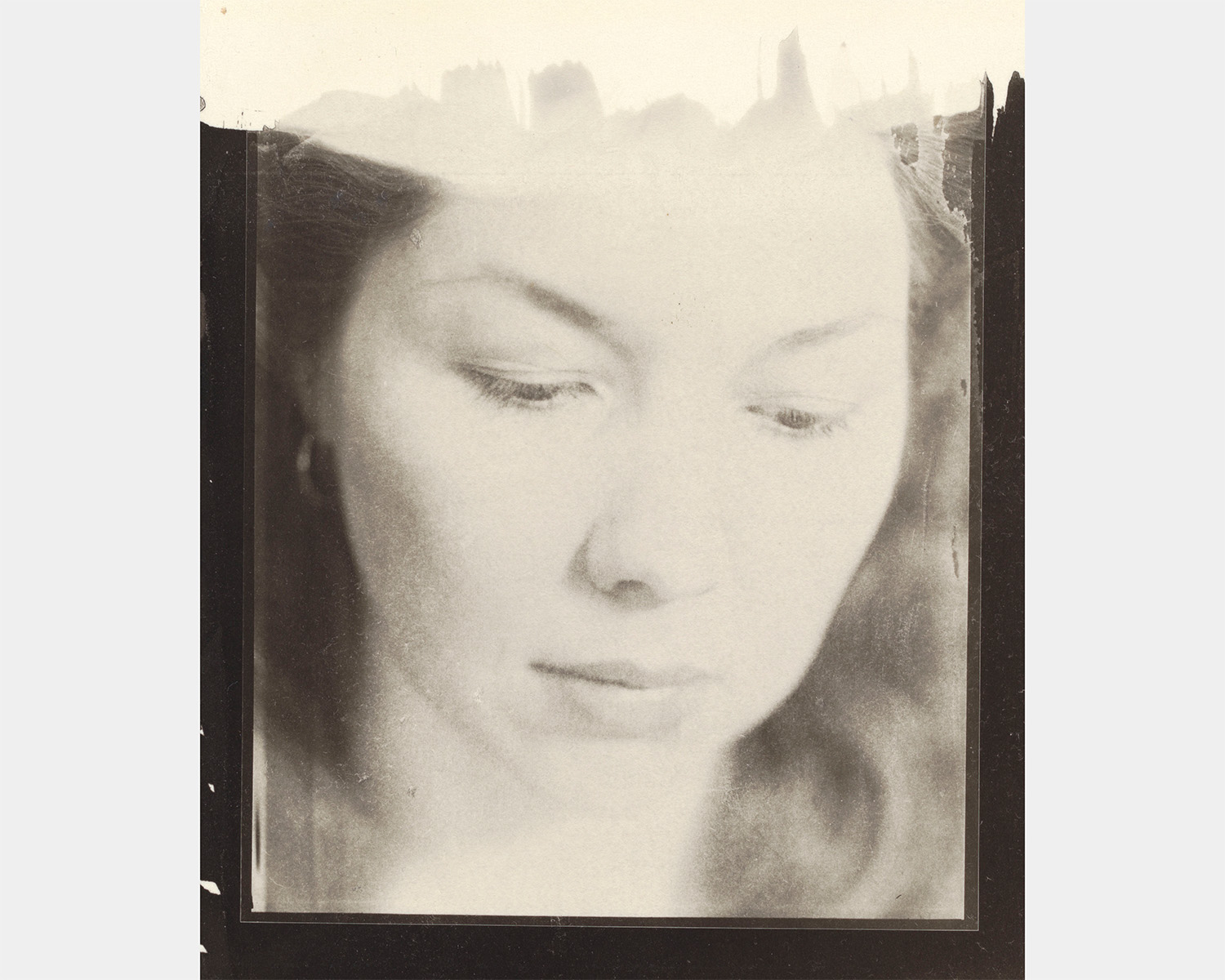 A black and white portrait of a white woman looking down