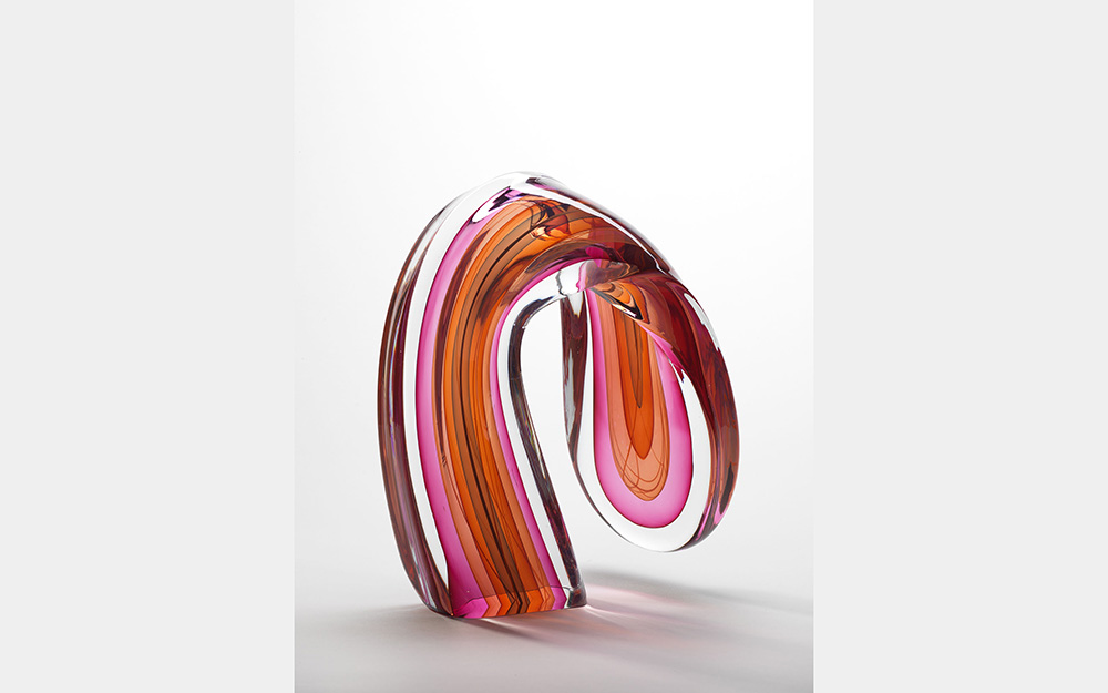 A curving glass form made from layers of pink and orange