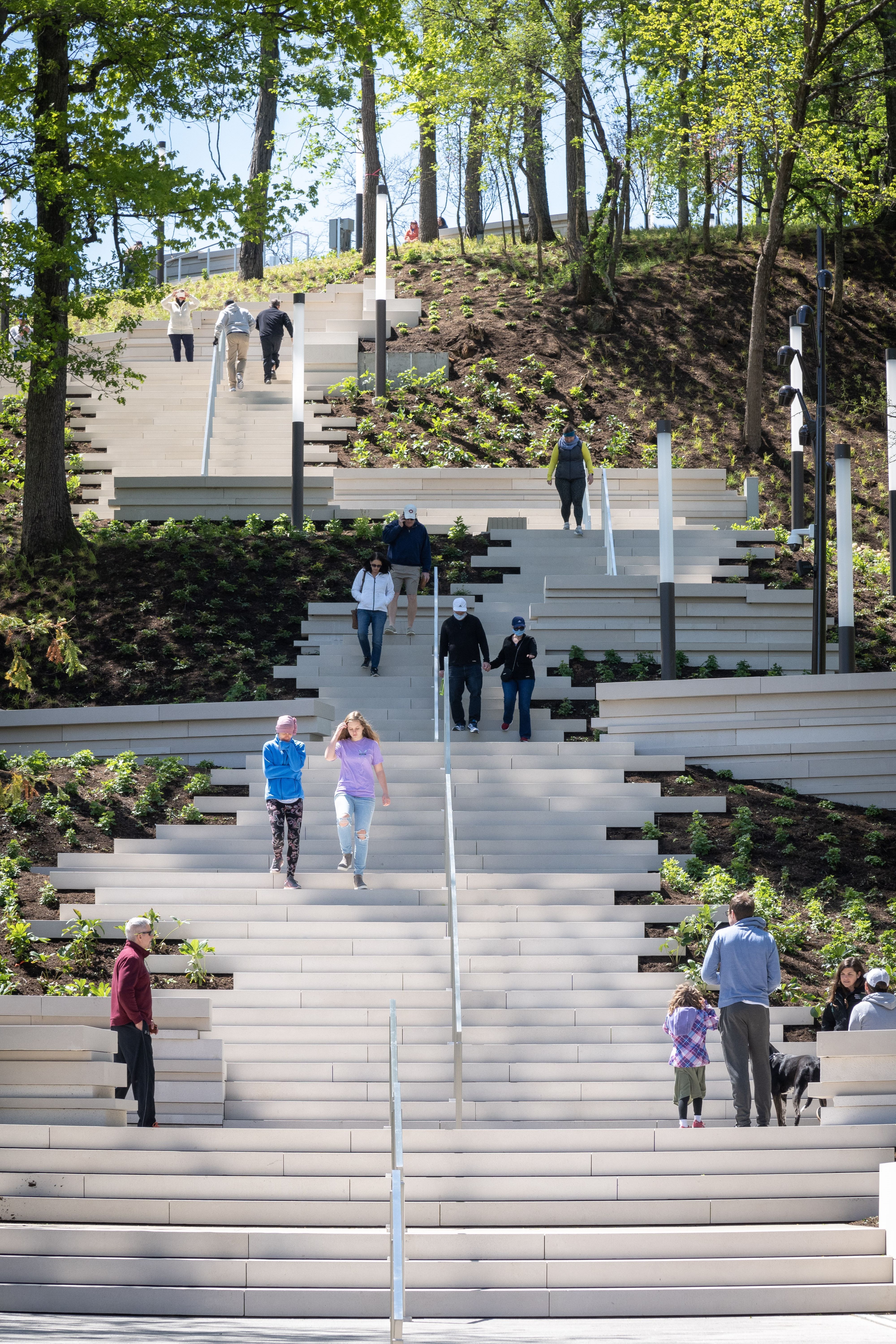 People walking up and down a broad, stone, outdoor staircase.