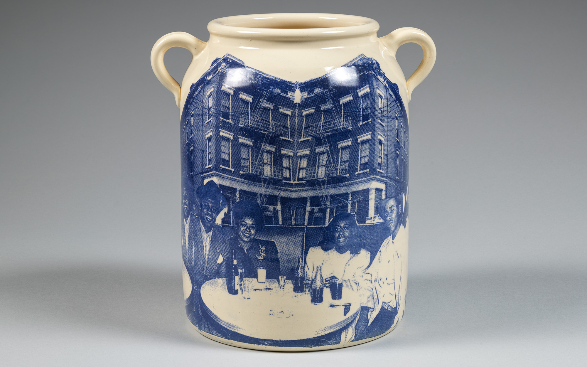 A large jug with a print of a group of Black people at a table in front of a building